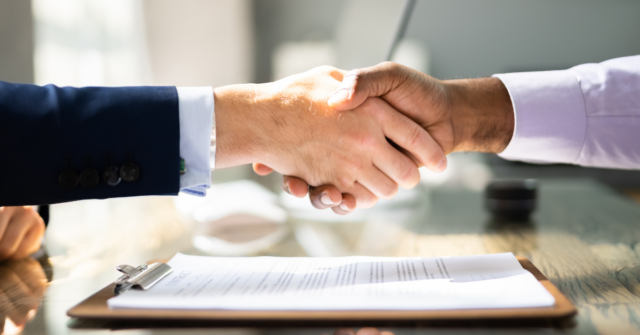white man and black man shaking hands over a business deal 